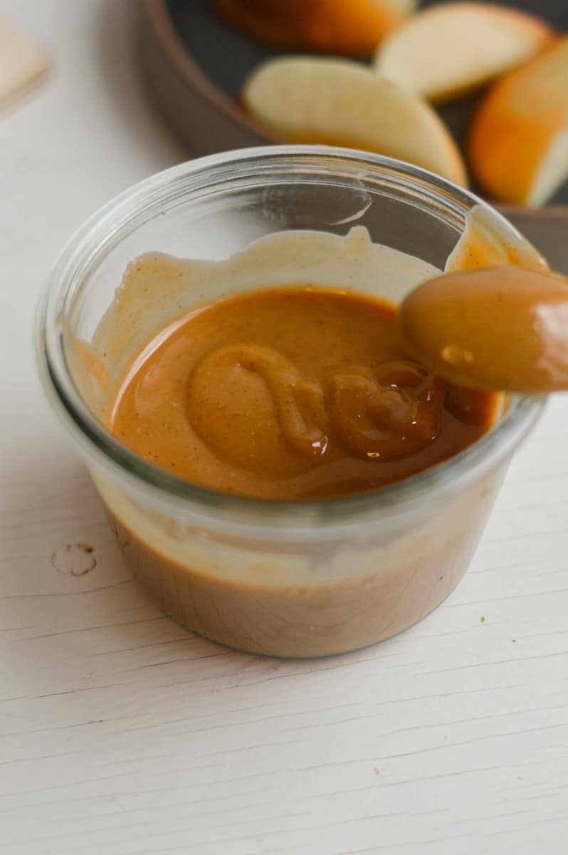Vegan caramel with apple slices in the background.