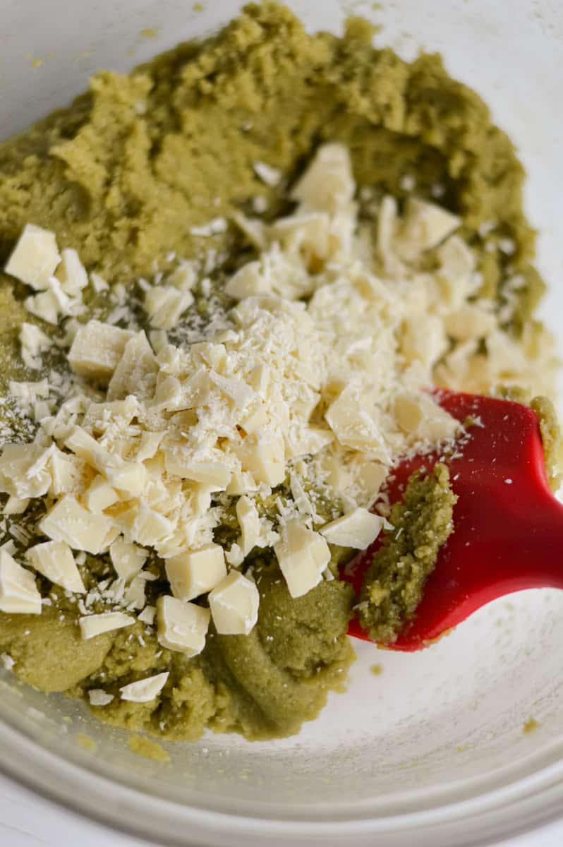 Adding white chocolate to matcha cookie dough. 