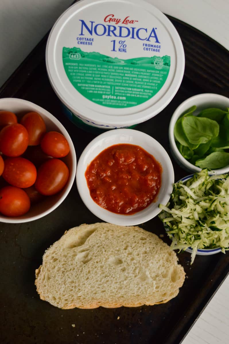 Ingredients for cottage cheese toast including cherry tomatoes, bread, and cottage cheese.