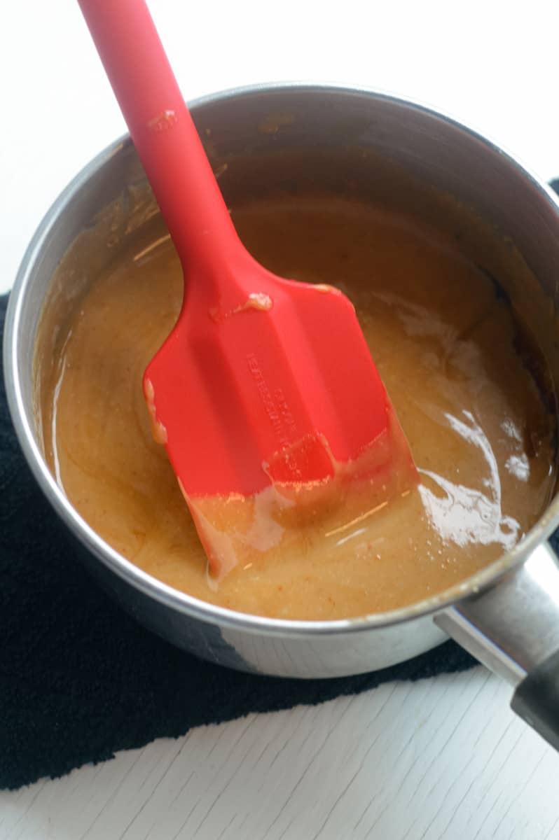 Whisking together vegan caramel in a pot.