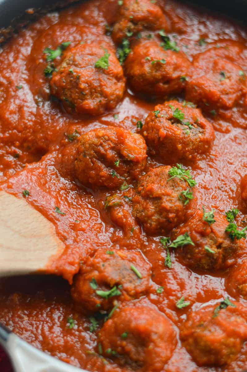 Adding tomato sauce to tofu meatballs.