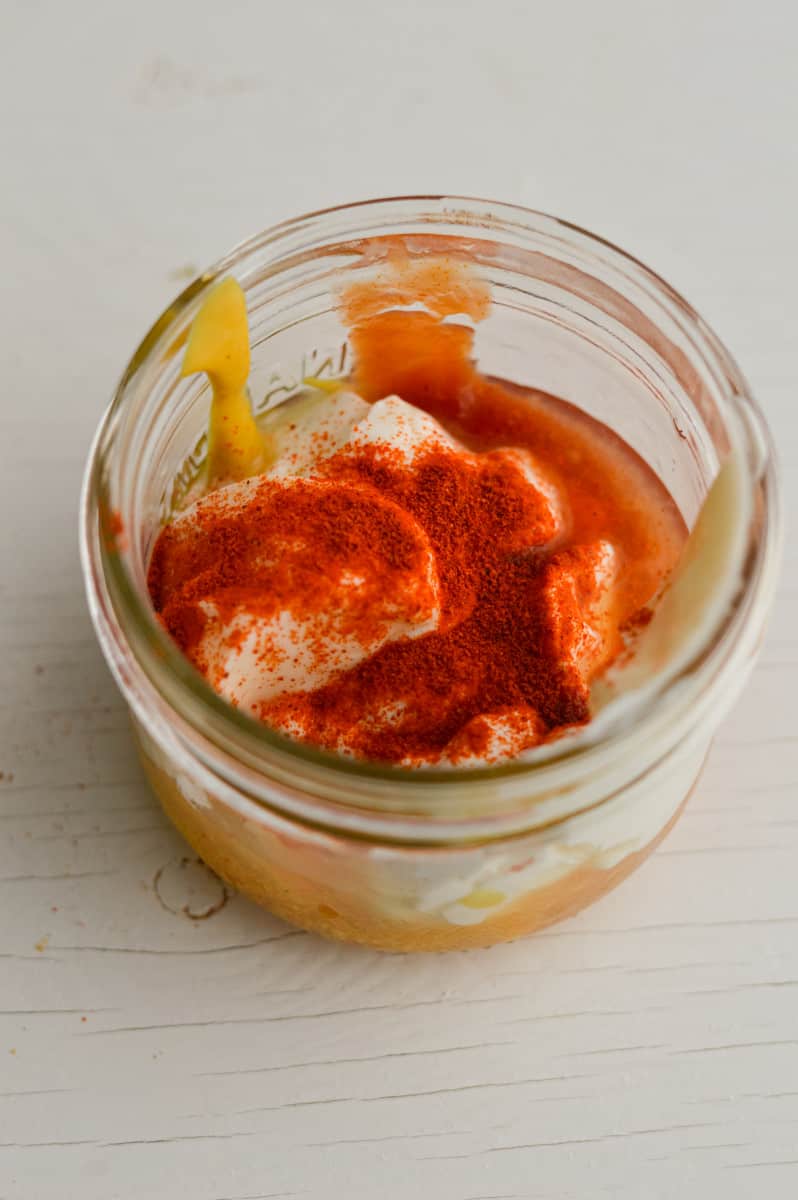 Mixing together mayo, yogurt, ketchup, mustard, pickle juice and spices.