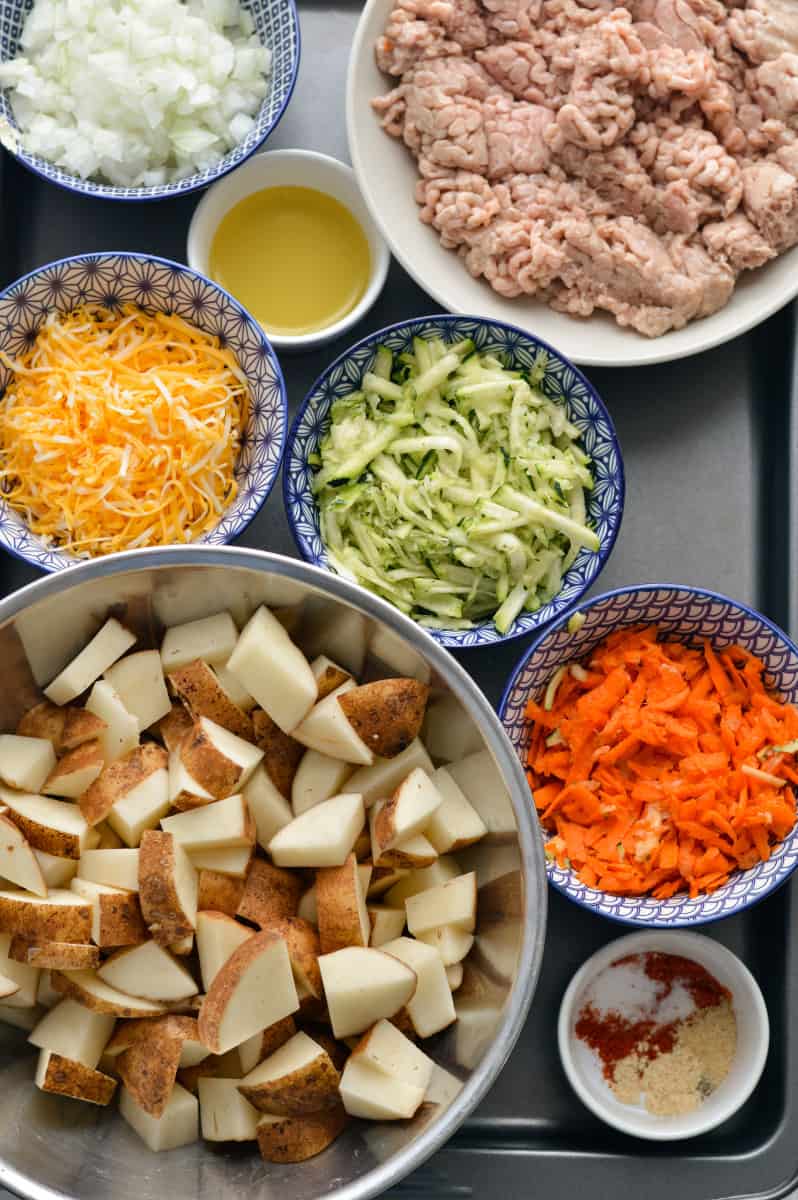 Ingredients for big mac casserole including potatoes, ground meat, veggies and cheese.
