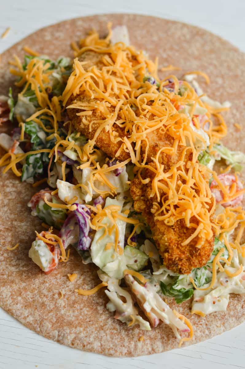 Adding shredded cheese to wraps.