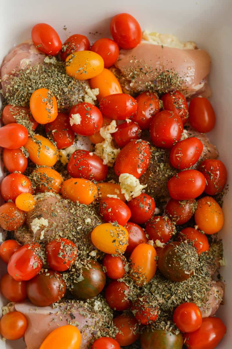 Raw chicken thighs with spices and cherry tomatoes.