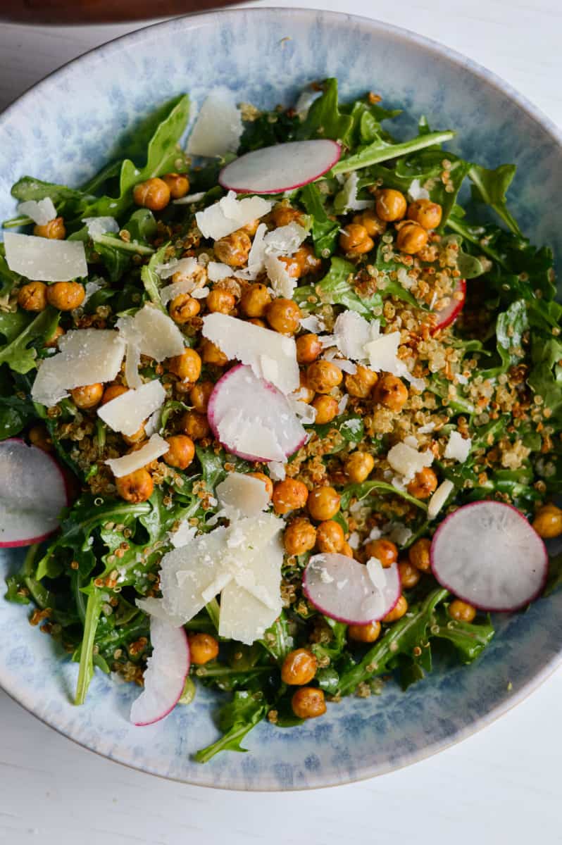 Close up of arugula quinoa salad topped with crispy chickpeas and quinoa.