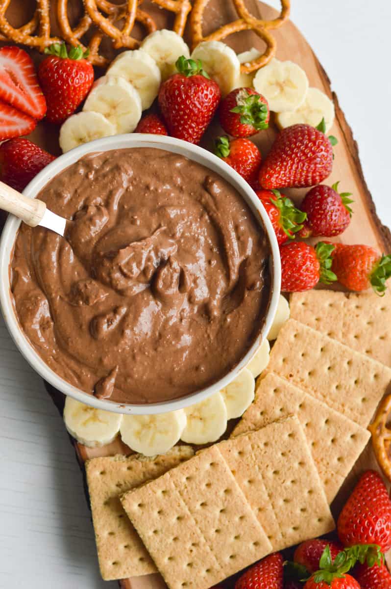 Birds eye of a dessert board with graham crackers, fruit, pretzels and chocolate fruit dip.