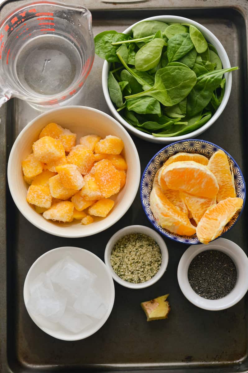 Ingredients for iron rich smoothie including spinach, mango, oranges and hemp seeds.