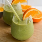 Two mango iron rich smoothies served with orange slices.