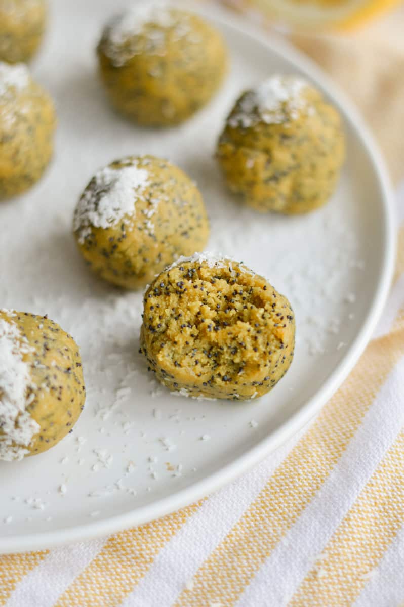 Lemon turmeric energy balls on a plate, with a bite.