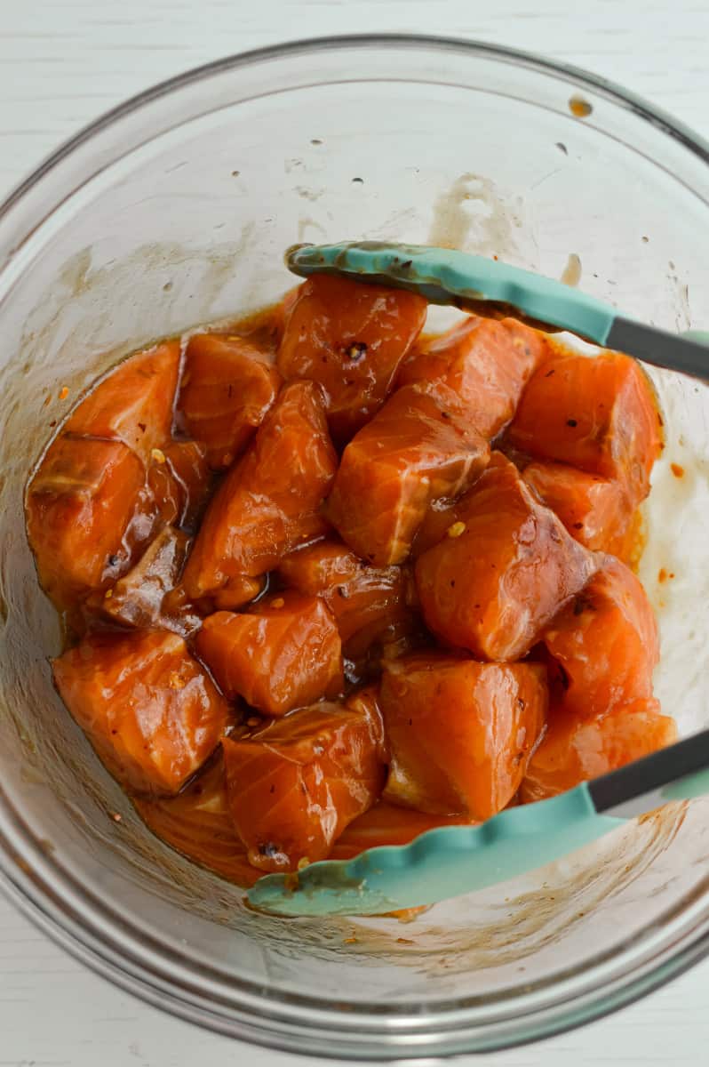 Mixing salmon with tongs.