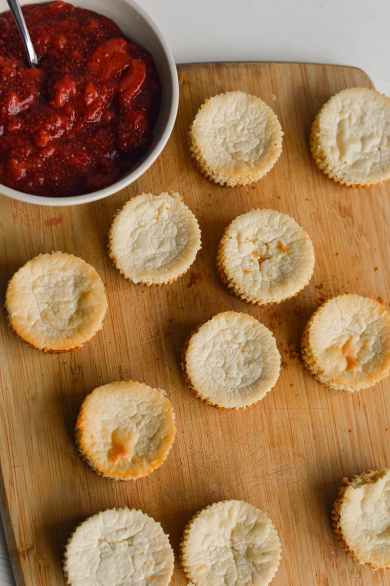 Mini protein cheesecakes on a board, ready to be topped with chia jam.