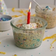 Birthday cake overnight oats with whipped cream and a candle.