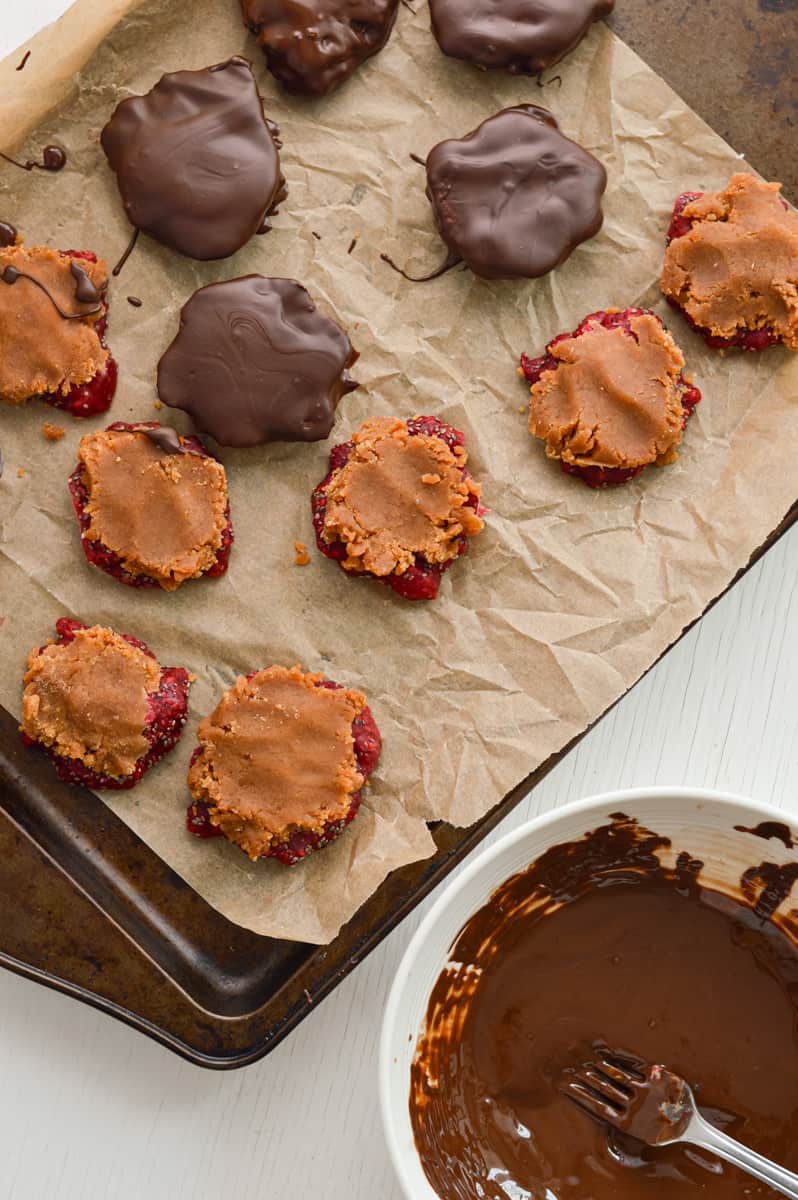 Dipping jam bites in melted chocolate.