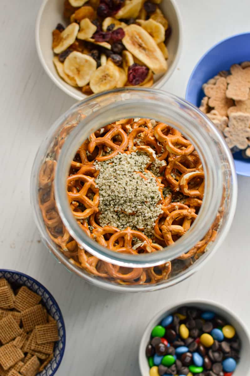 Adding trail mix ingredients to a jar.