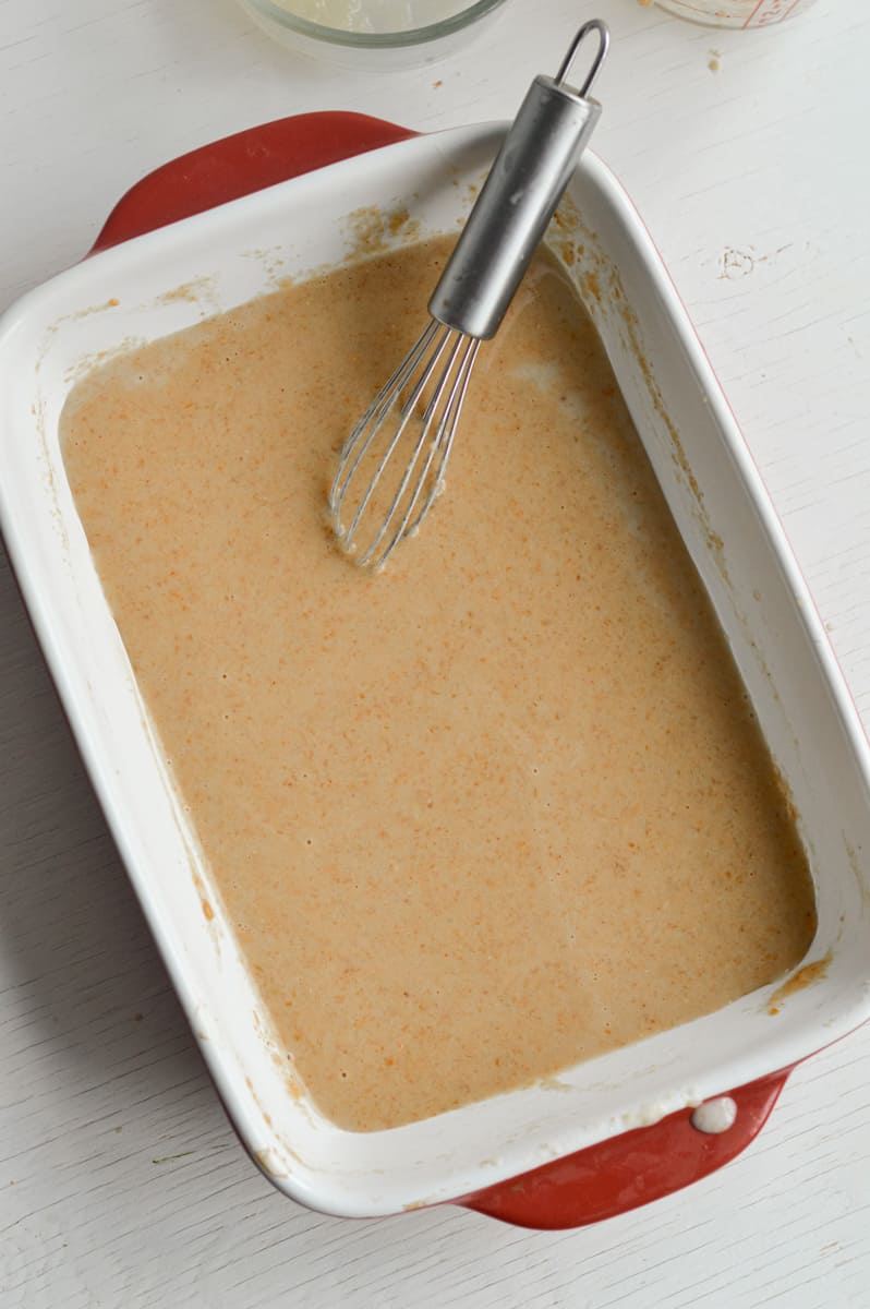 Whisking together eggs, applesauce, milk, maple syrup, vanilla extract, maple syrup and peanut butter.