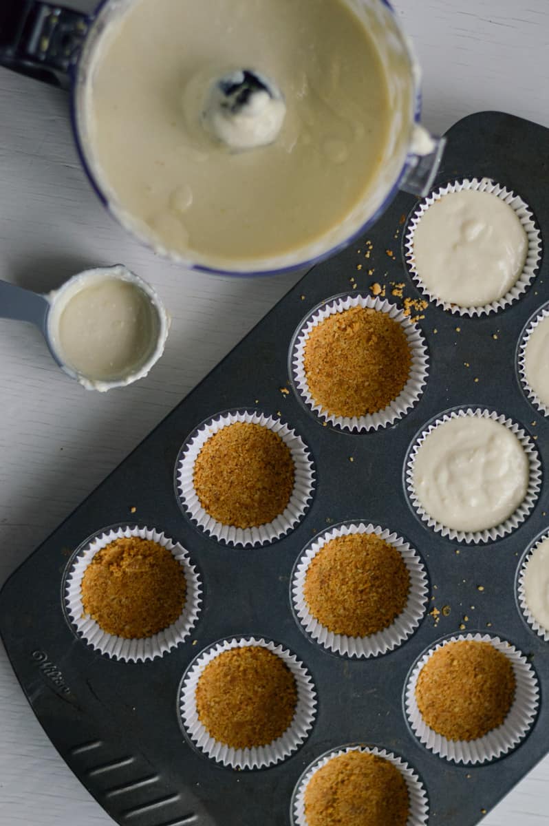 Pouring cheesecake filling into muffin liners.
