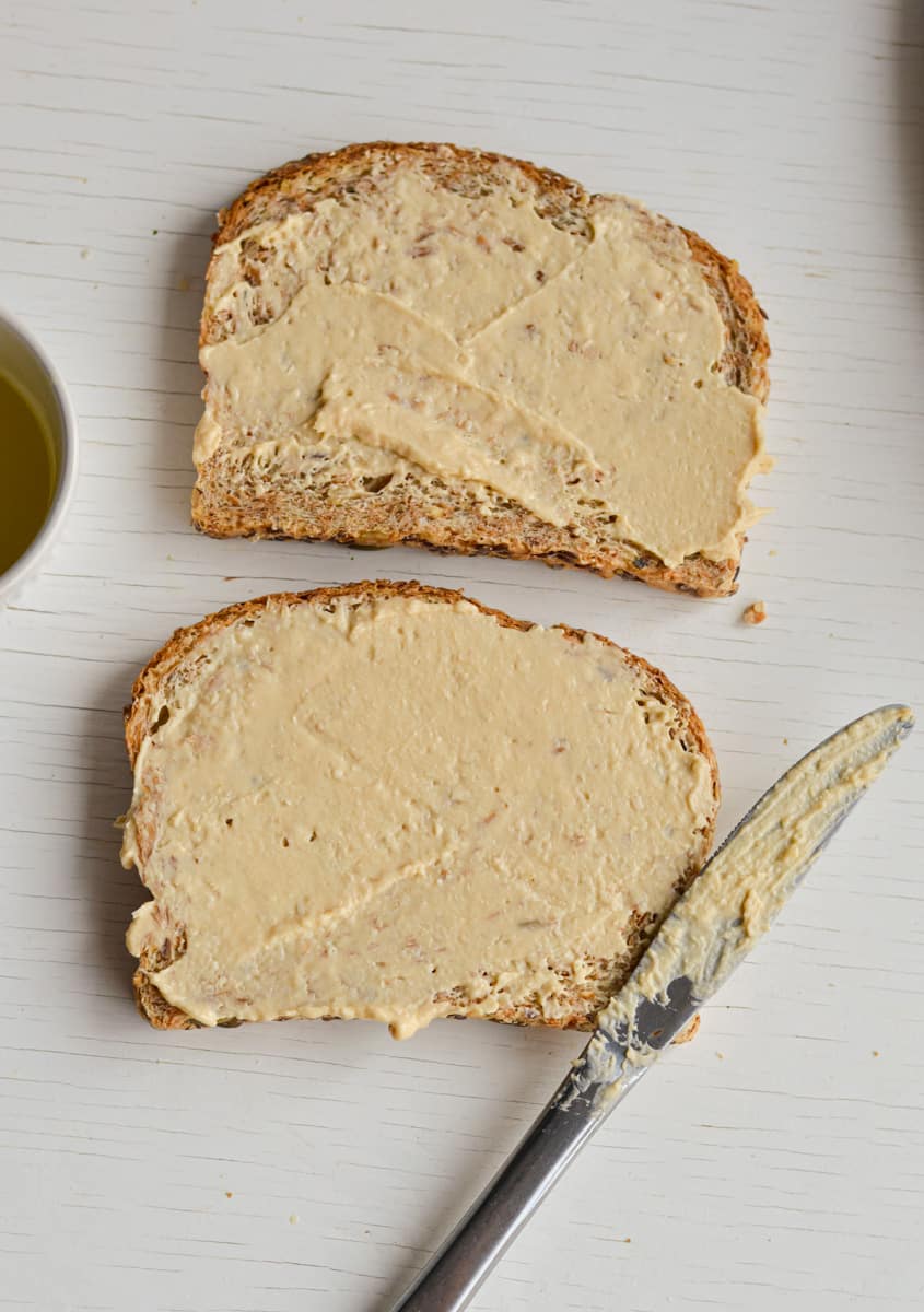 Spreading hummus on slices of bread.