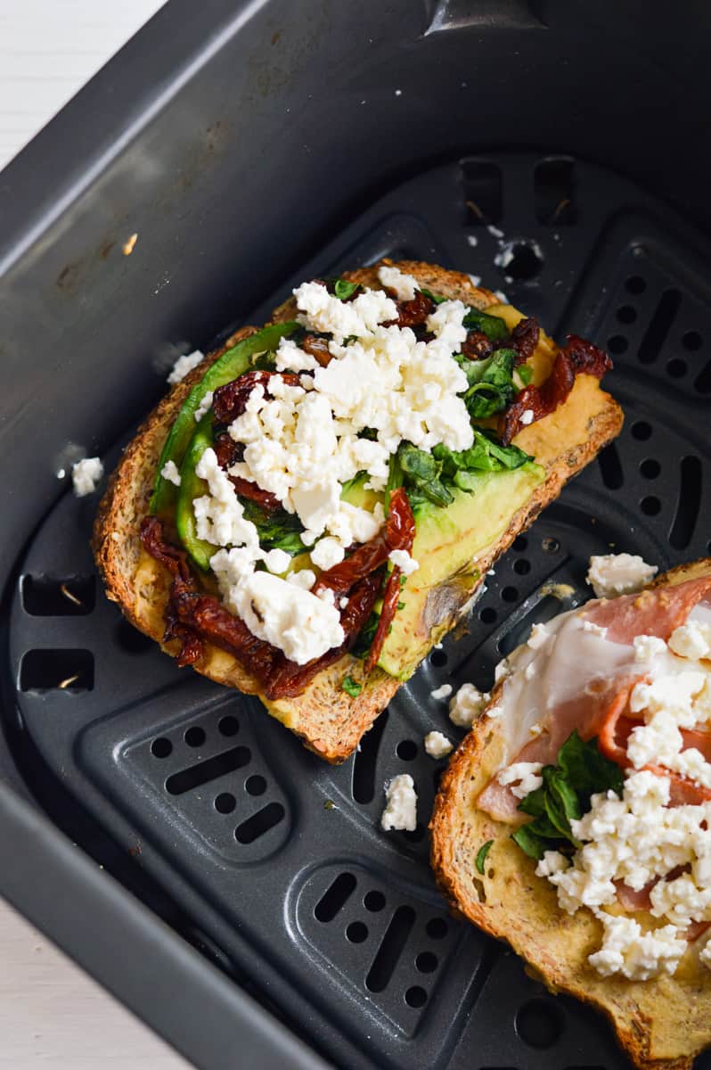 Sprinkling feta cheese on breakfast sandwich halves.