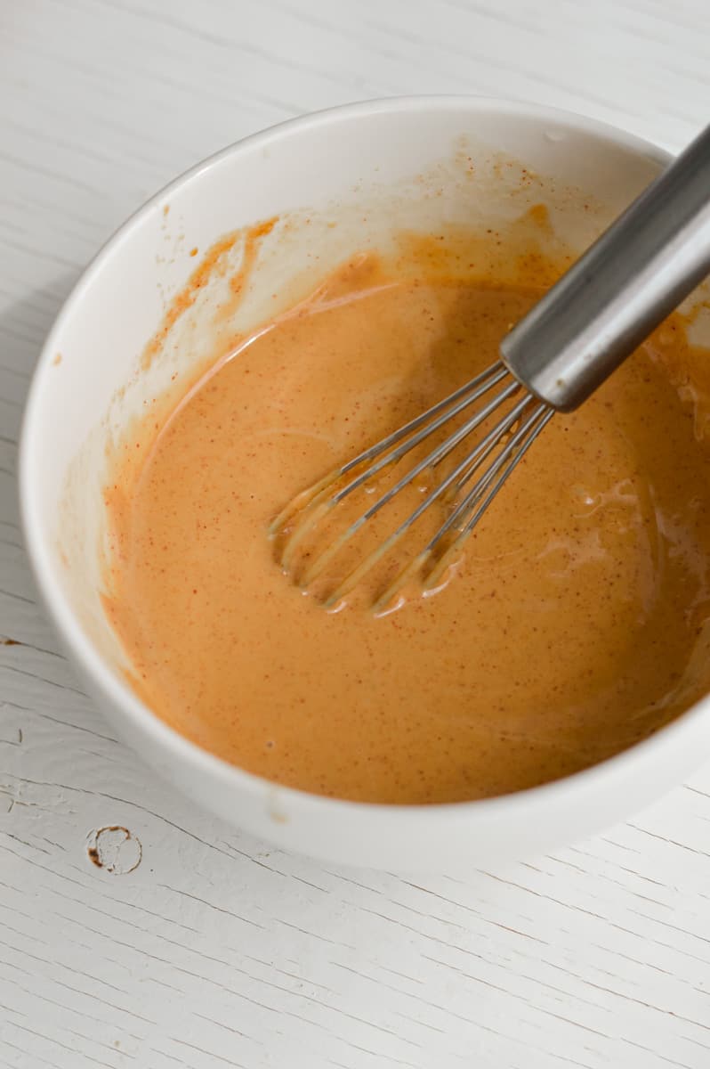 Whisking peanut sauce in a bowl.