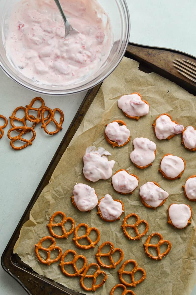 Adding strawberry yogurt to pretzels.