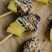 Chocolate covered pineapple pieces on skewers, coated in shredded coconut.