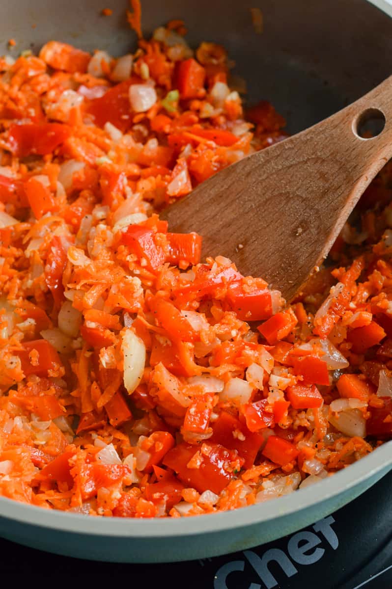 Cooking onion, garlic, peppesr and carrot in a skillet.