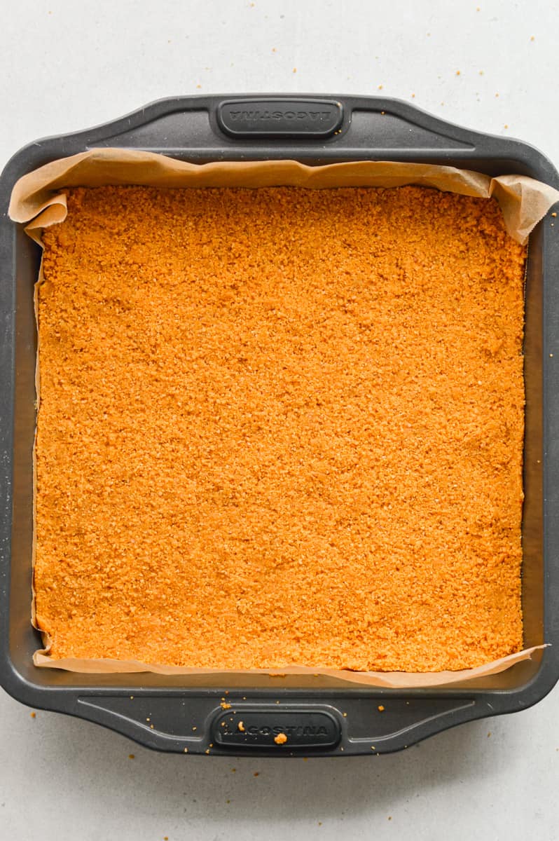 Pressing graham cracker crumbs to form crust.