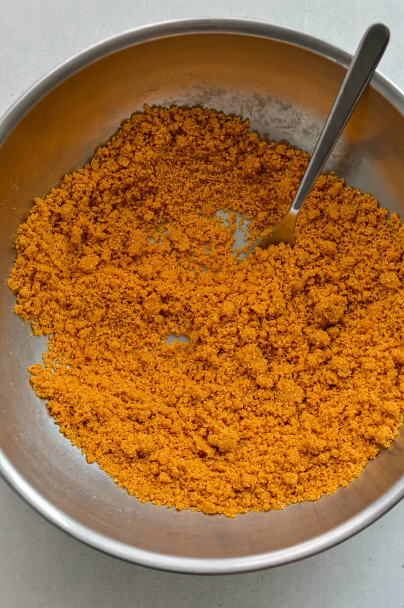 Mixing graham cracker crumbs with melted butter.