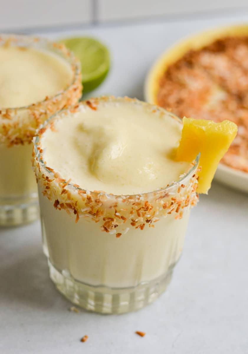 Healthy pina colada mocktail wiht a slice of pineapple and toasted coconut rim.