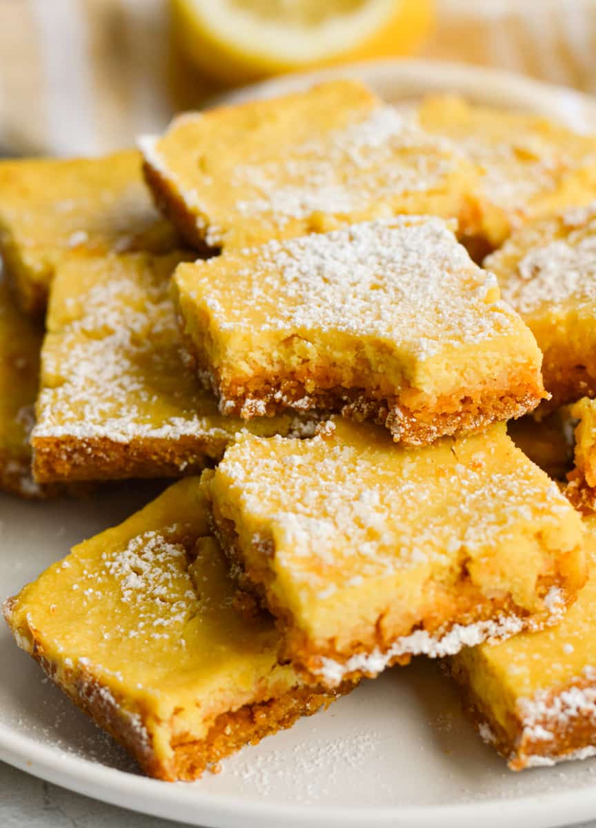 Plate of lemon bars with graham cracker crust with bites taken out.