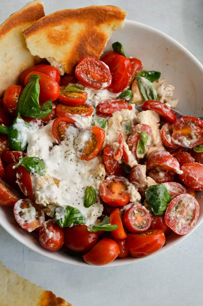 Mixing burrata caprese salad and serving with pita.