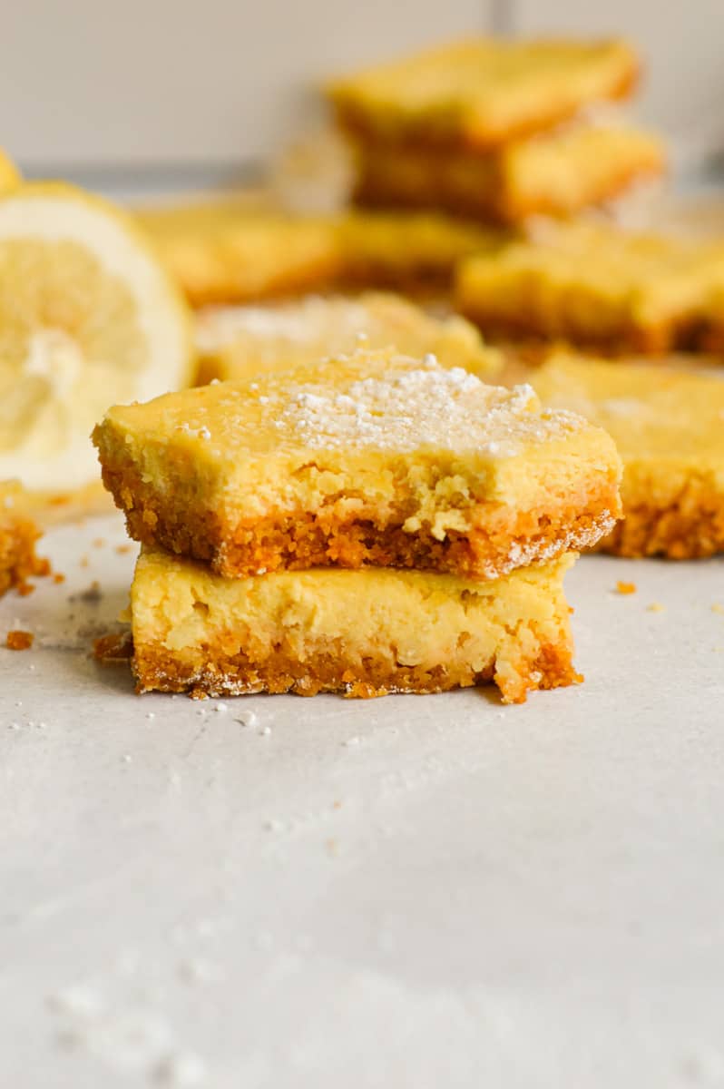 Two lemon bars with graham cracker crust, stacked.