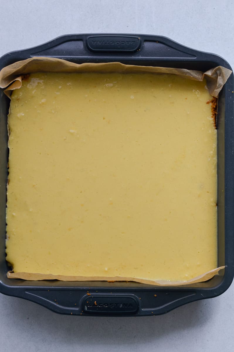 Pouring lemon filling onto graham cracker crust.