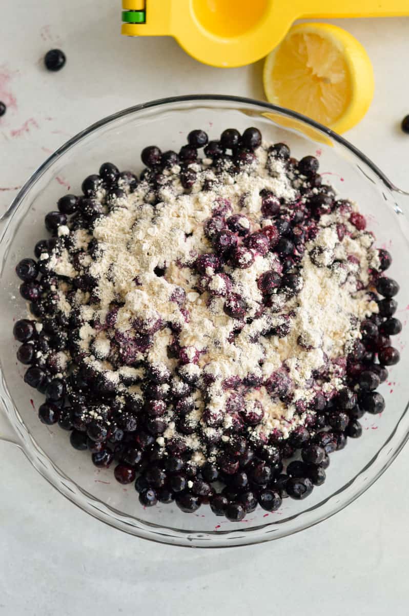Mixing blueberries, oat flour, lemon and vanilla in a bowl. 