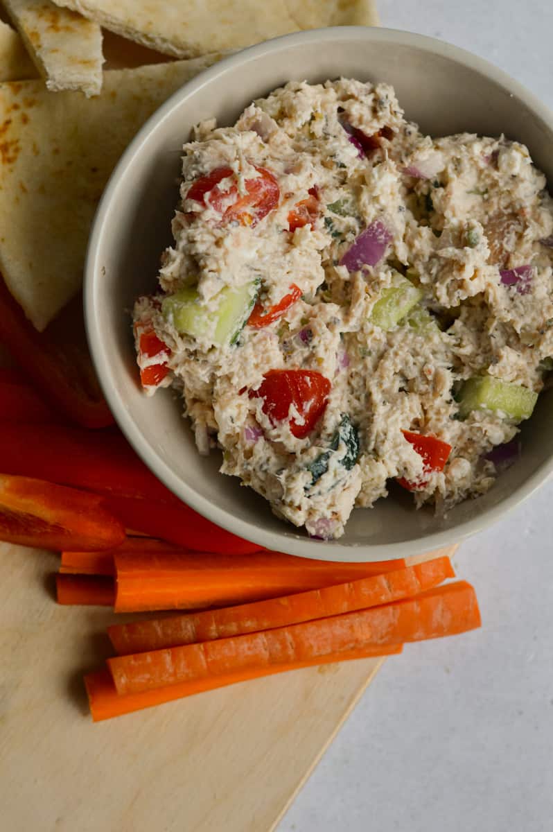 Bowl of tzatziki salad served with carrot sticks.