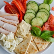 Snack plate ideas for a girl dinner including turkey, veggies, pita, hummus and cheese.