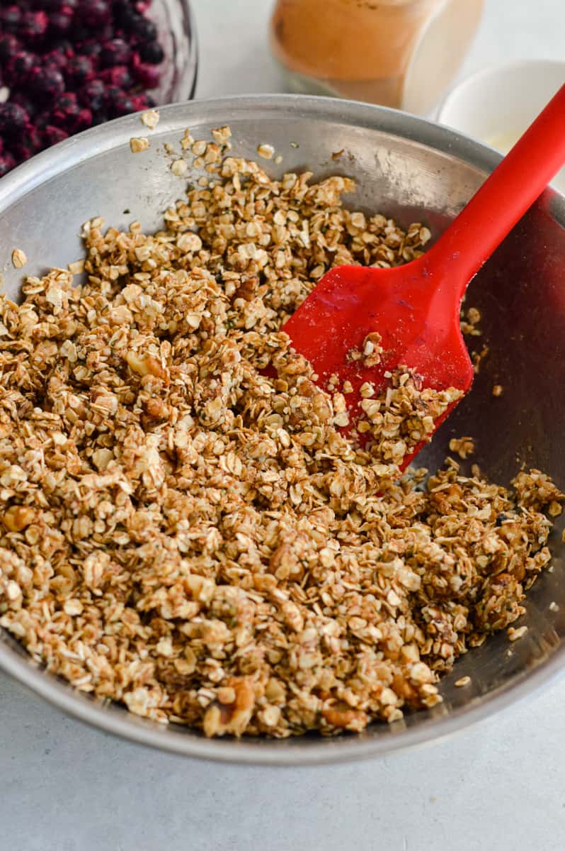Mixing oats, oat flour, cinnamon, honey and butter to form crisp topping.