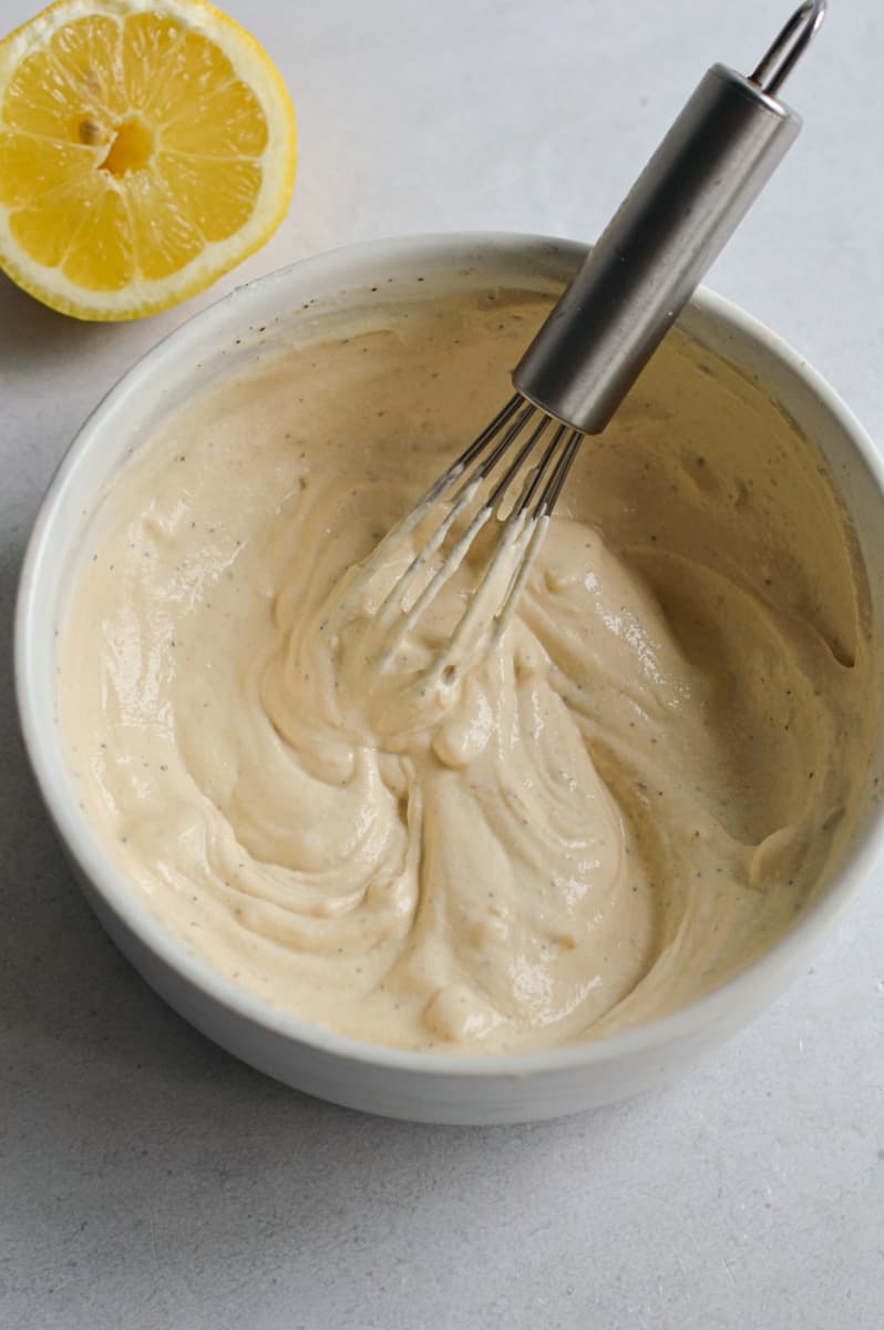 Whisking tahini sauce with water to thin.