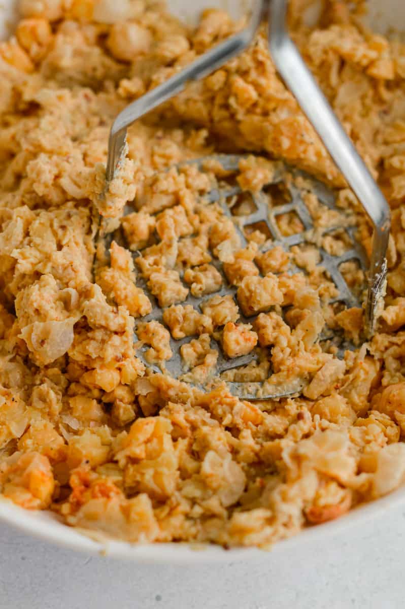 Smashing chickpeas with a potato masher.
