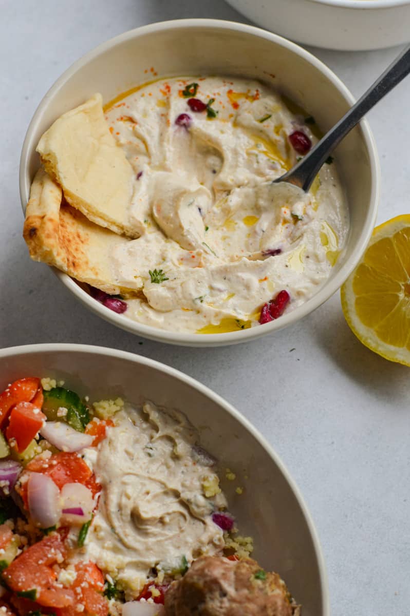 Adding tahini sauce to mediterranean bowls.