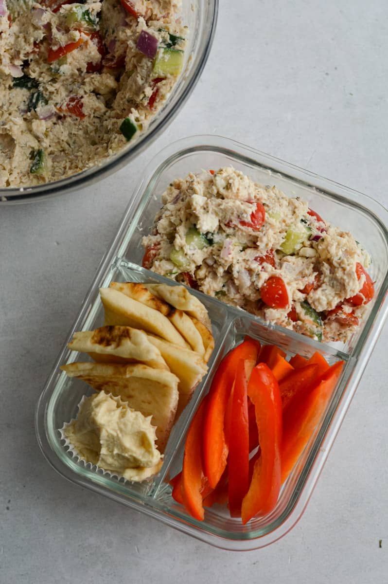 Serving tzatziki salad in an adult lunchable with veggies and pita.