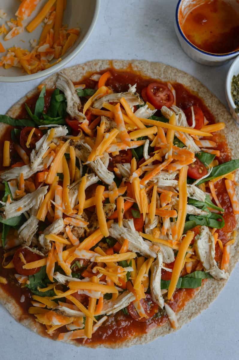 Adding cheese onto tortilla pizza.