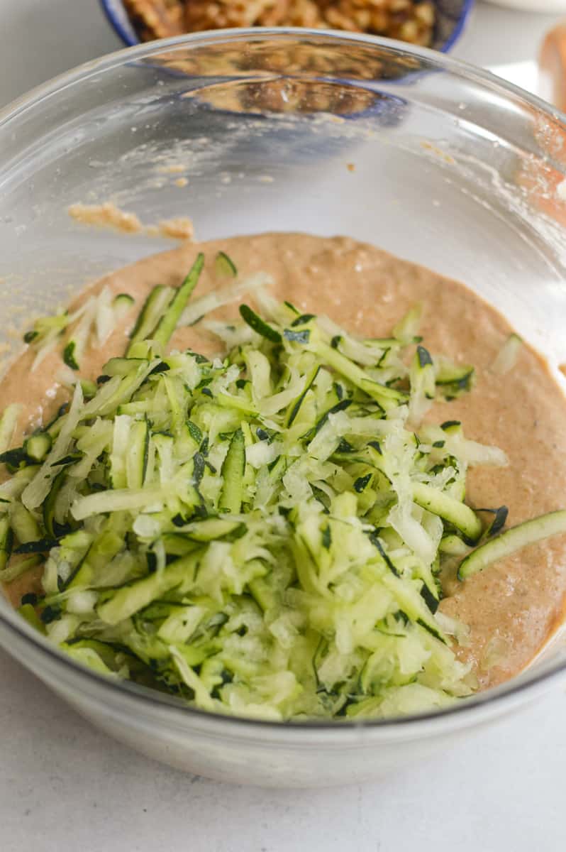 Folding shredded zucchini into muffin batter.