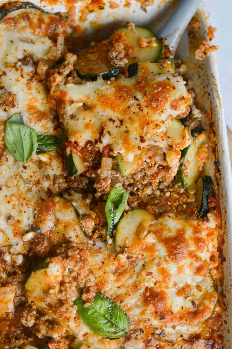 Close up of grounnd beef zucchini casserole topped with fresh basil.