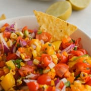 Dipping a chip in mango corn salsa.
