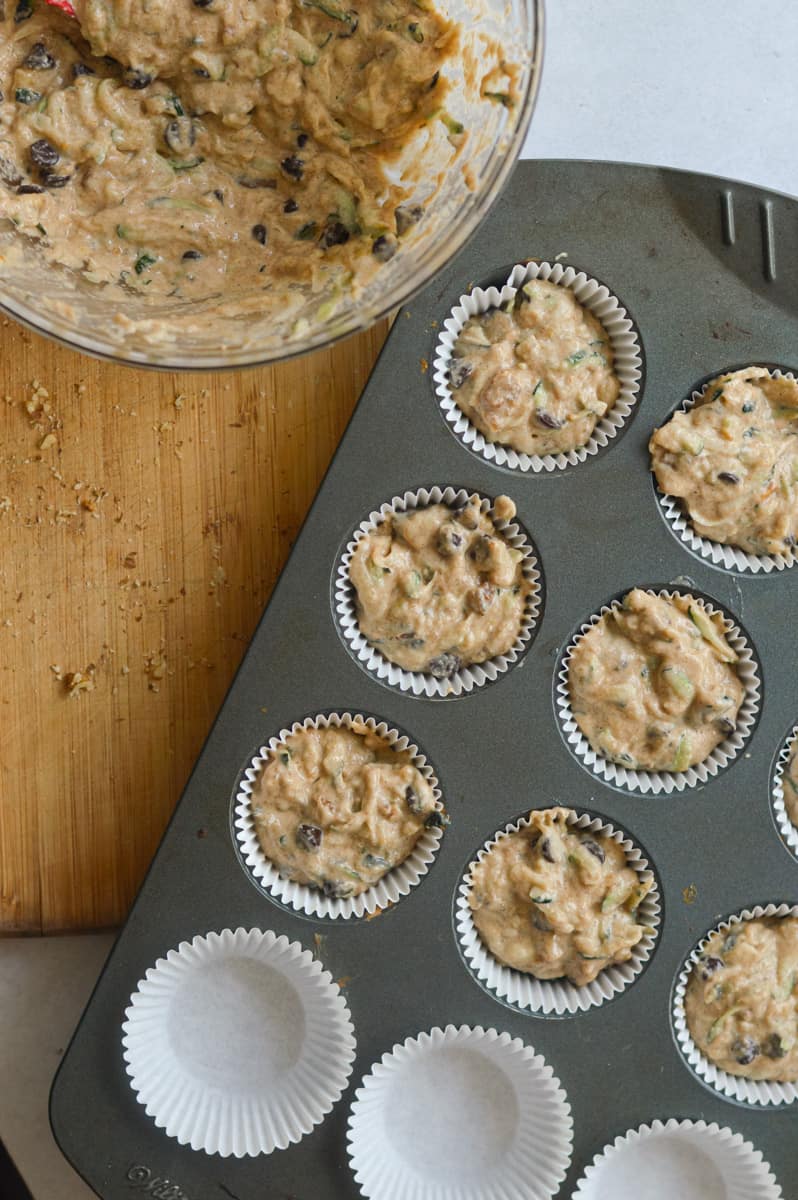 Scooping batter into lined muffin tray.