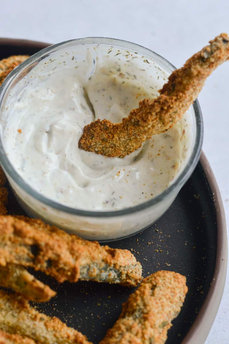 Dipping a vegan zucchini fry into garlic yogurt dip.