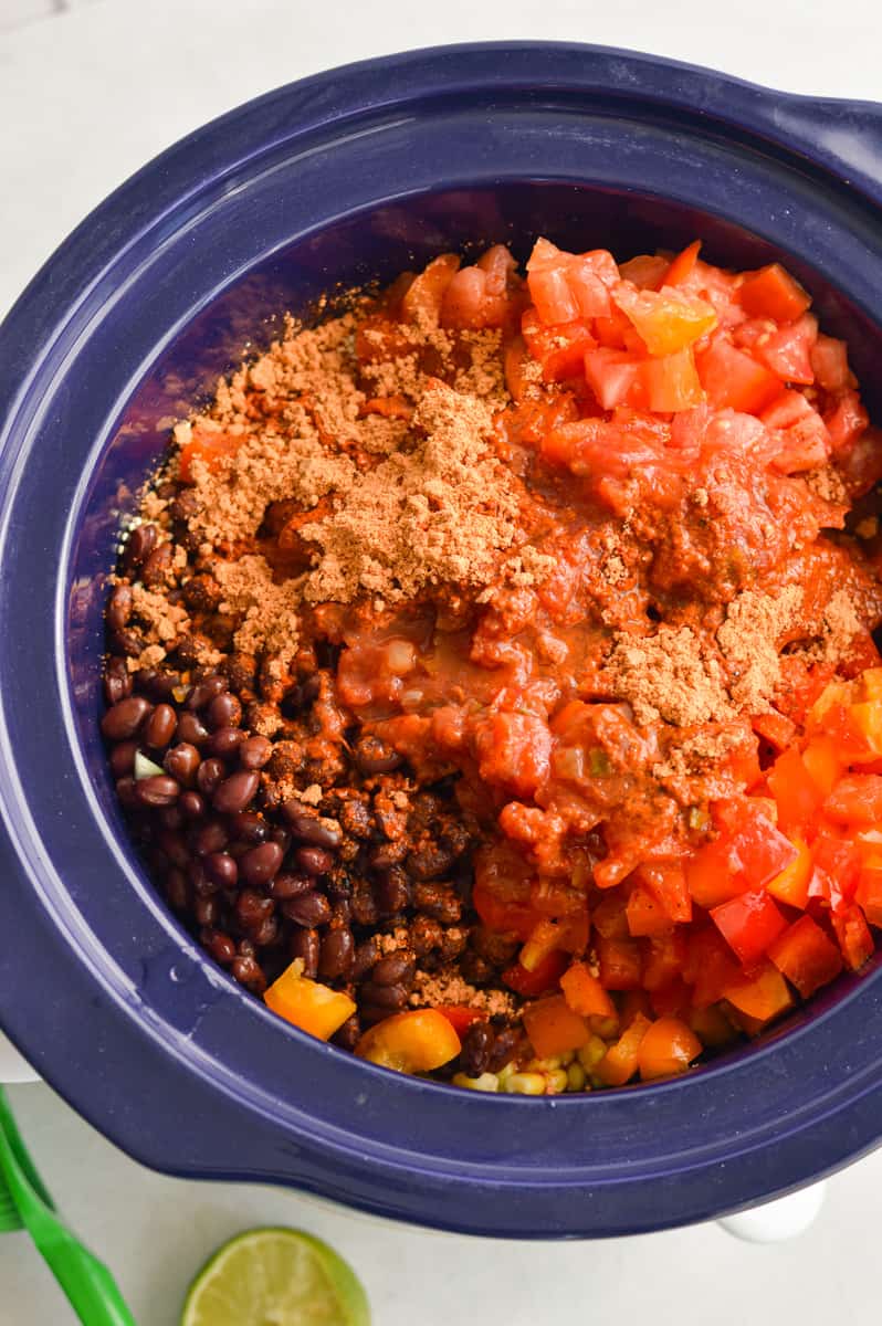 Adding diced tomatoes, beans, spices, veggies, quinoa, salsa and chicken broth to slow cooker.