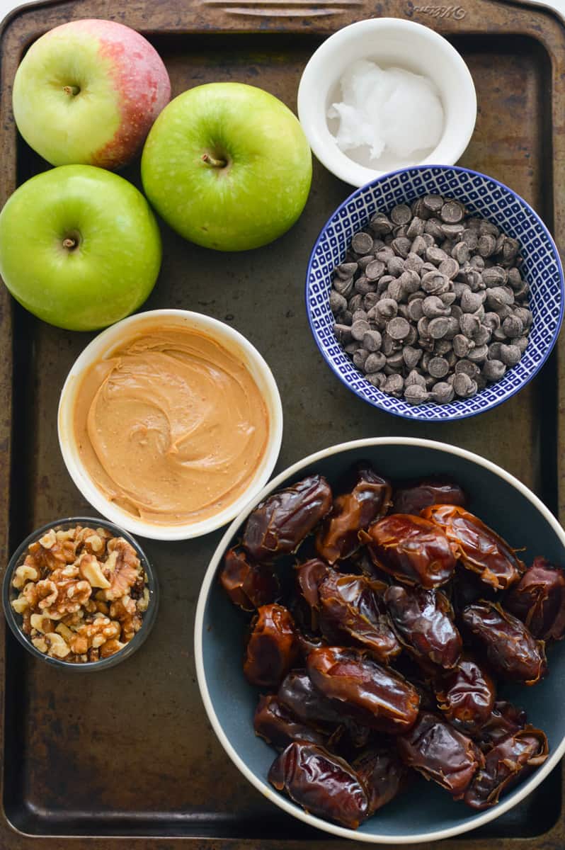 Ingredients including dates, peanut butter, chocolate chips, apple, coconut oil and walnuts.